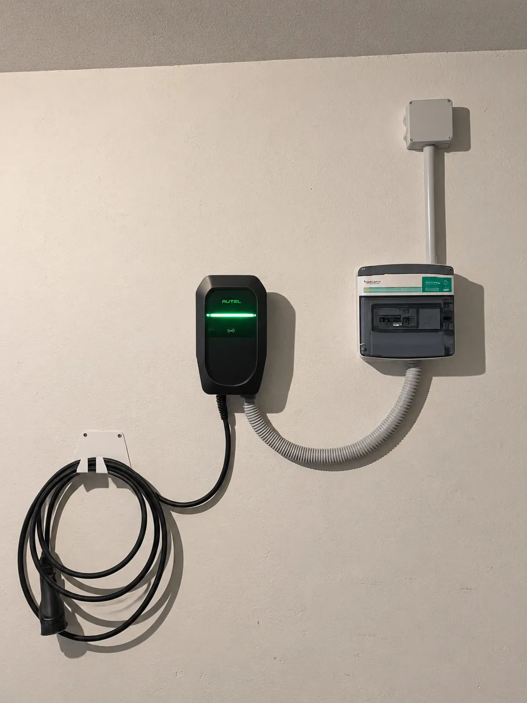 Cargador Autel instalado en la pared de un garaje particular junto a su cuadro de protección, con el cable recogido en un soporte